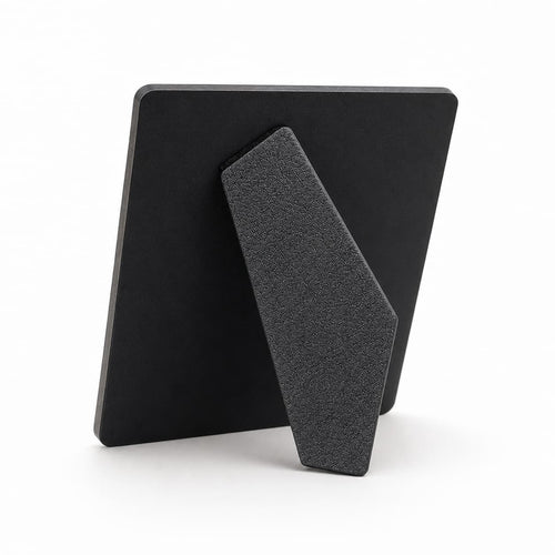 A minimalist black picture frame with a textured, angled kickstand, shown from the back on a clean white background.